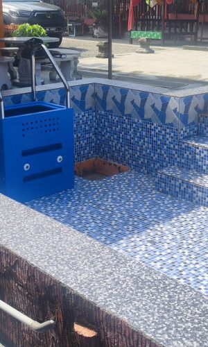 Wall-mounted blue plug and play pool filtration unit installed inside an empty tiled pool during construction.