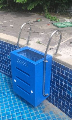 Wall-mounted blue plug and play pool filter unit integrated with stainless steel pool entry handrails.