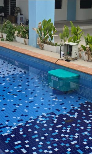 Wide shot of a teal plug and play pool filter running in a blue tiled residential swimming pool.