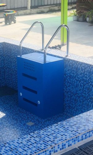 Wall-hung blue plug and play pool filter unit mounted in an empty mosaic-tiled swimming pool.