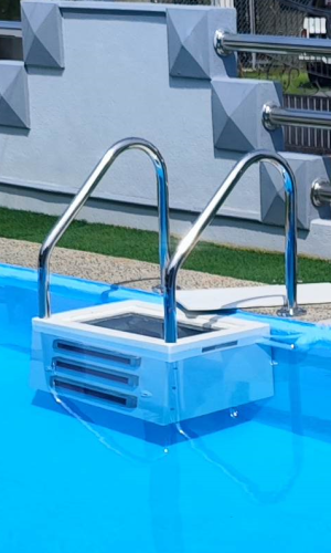 Outdoor blue residential swimming pool featuring a wall-mounted white plug and play filtration system and stainless steel entry ladder.